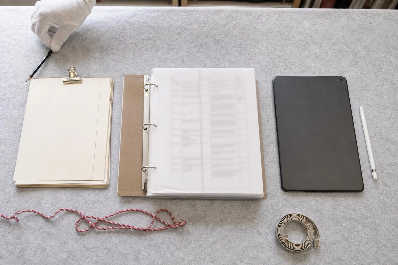 Trois supports de relevé posés côte à côte sur une table de réserve, une liasse de fiches cartonnées, un classeur ouvert et une tablette retournée